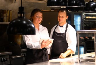 Illustrationsfoto af to personer foran en iPad i et køkken.