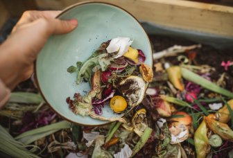 Fotoaf en person, der smider madrester i madaffald.