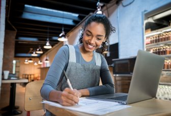 Foto af en kvinde, der arbejder på en computer i en kantine.