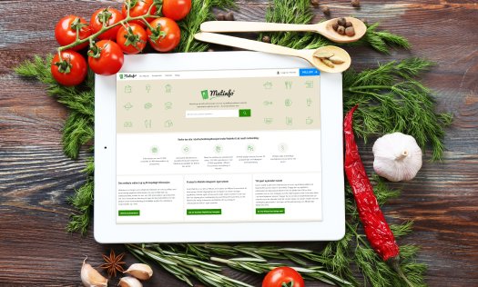 En iPad med Matinfo-siden på skærmen ligger på et bord med grøntsager. Foto